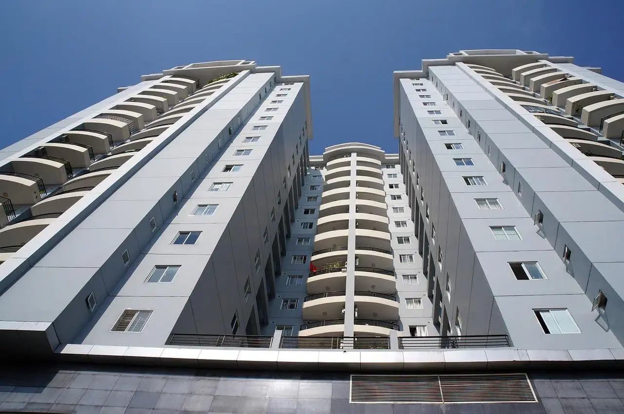Dois prédios residenciais altos vistos de baixo, com sacadas brancas